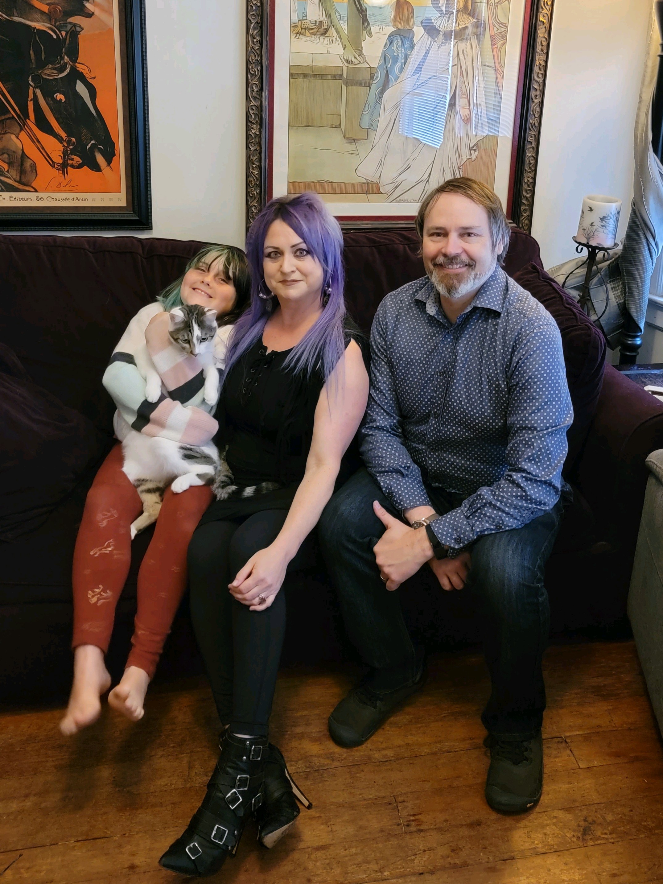 family with two parents and one child sitting on a couch